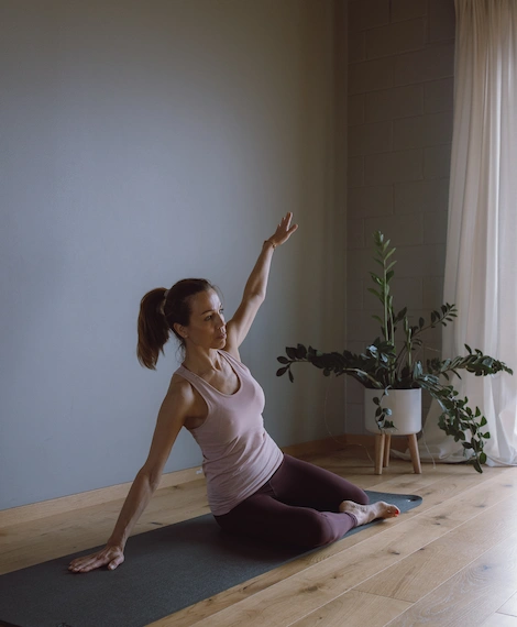 Pilates matil – naine istub külgtõstes, harjutades liikuvust ja kehatunnetust valgusküllases stuudios.